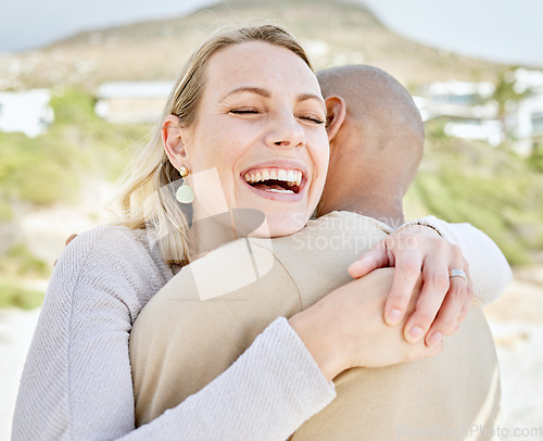 Image of Happy, hug and couple on a beach together smile in nature feeling love and happiness outdoor. Laughing, smiling and romantic experience for an anniversary or engagement announcement at the sea