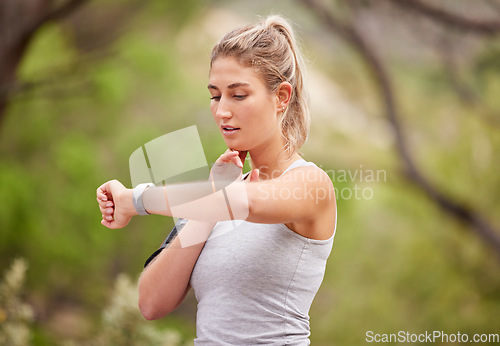 Image of Fitness, woman and watch checking time in nature for exercise, workout or training in the outdoors. Active female runner looking at wrist monitoring heart rate, pulse or activity for healthy cardio