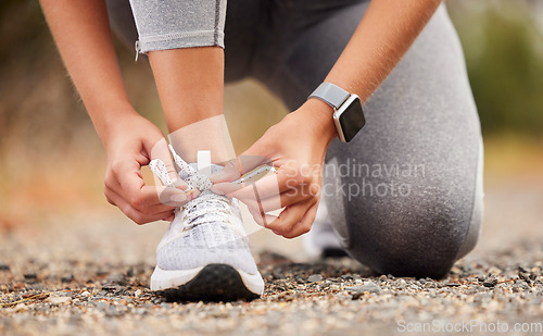 Image of Shoes, fitness and exercise with a sports woman tying her laces before training, running or a workout. Hands, health and cardio with a female runner or athlete getting ready for an endurance run