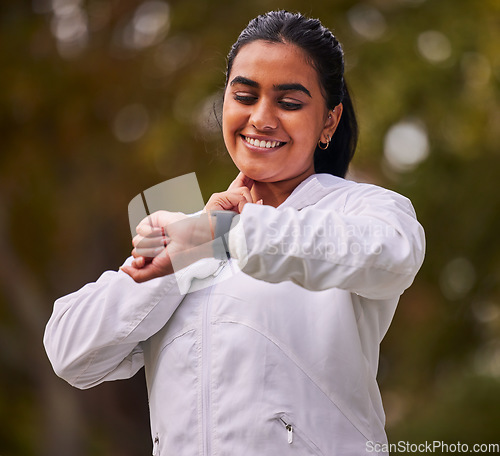 Image of Pulse, fitness and woman running in the park, on a break to check heart rate on sports watch. Indian girl doing exercise, training and workout in nature for wellness, cardio and healthy lifestyle