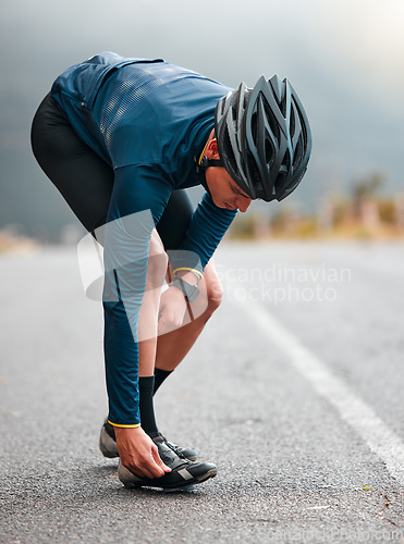 Image of Cycling, man and shoes preparation on road for outdoor sports adventure, triathlon or workout. Fitness, training and athlete cyclist man on street with helmet getting ready for cycle exercise.