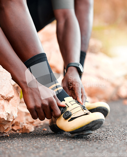 Image of Black man, cycling shoes and fitness in sports motivation for cardio exercise, training or workout in the outdoors. African American male tying shoe for cycle tour on a road for sport competition