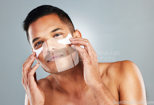 Image of Model, skincare and eye mask for man in portrait for health, wellness and cosmetics with grey backdrop. Face, cosmetic and facial for beauty, self love and self care with studio background for care