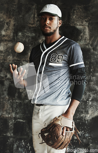 Image of Baseball, sports and uniform with a man athlete on a dark background wearing a mitt while holding a ball. Portrait, sport and confident with a male baseball player standing against a dugout wall