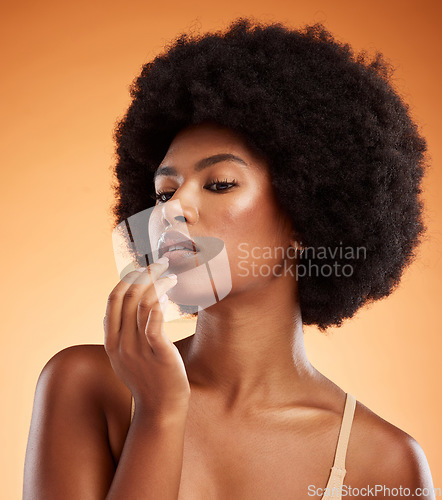 Image of Model woman with lip balm makeup in studio, portrait with skincare product advertising or natural cosmetic on face. Lip gloss on mouth, beauty on orange background or moisturizer cream lipstick