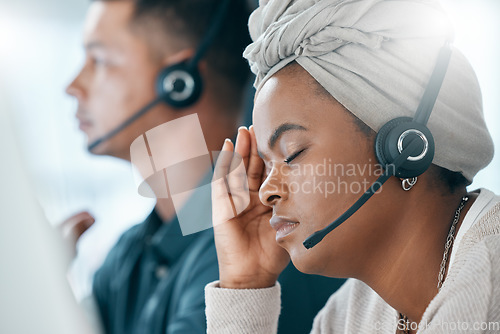 Image of Headset, call center and black woman with headache, stress and anxious being overworked in office. Frustrated, customer support agent and burnout with depression, pain and migraine sitting at desk.