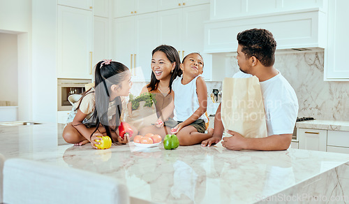 Image of Asian, family and vegetables in kitchen for laugh at table, happy or comic in bonding. Mom, dad and children with smile at counter for funny, joke or crazy with bags after shopping in home in Jakarta