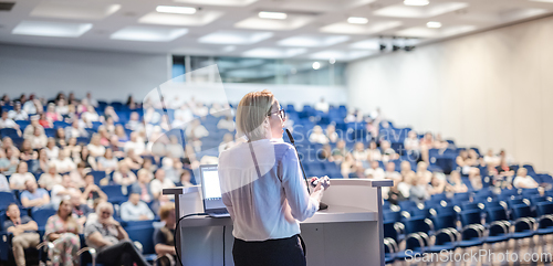 Image of Female speaker giving a talk on corporate business conference. Unrecognizable people in audience at conference hall. Business and Entrepreneurship event.