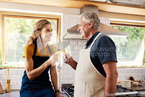 Image of Wine, cheers and senior couple in the kitchen to cook a mean for date, dinner or lunch at their home. Happy, smile and elderly man and woman in retirement drinking alcohol beverage while cooking food