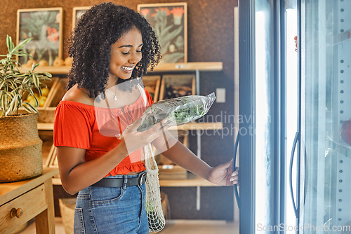 Image of Shopping, supermarket and customer with spinach in fridge reading label for price check, discount or sale promotion in store. Happy woman with lettuce or green leaf kale product in retail food store