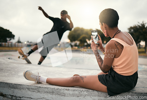 Image of Man on skateboard in park, woman photograph skater boyfriend in city on smartphone or urban lifestyle in Los Angeles. Street fashion, young edgy black couple streaming video online or social media