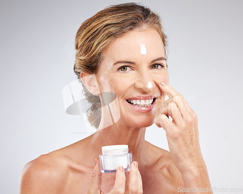 Image of Skincare, elderly and woman with facial cream or face cream product for healthy glowing face in studio portrait. Smile, mockup and happy mature beauty model grooming with sunscreen natural cosmetics