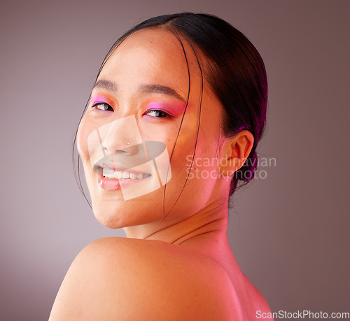 Image of Beauty, makeup and face of model in studio with neon, creative and color vaporwave, eyeshadow and mockup. Portrait, art and Chinese model smile, happy and relax with facial cosmetics grey background