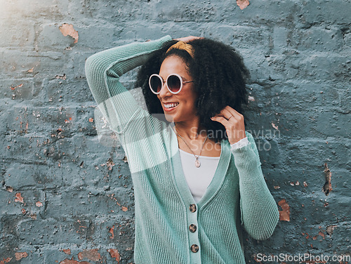 Image of Brazilian woman, fashion and sunglasses by city building wall for fun summer holiday, weekend break or urban vacation. Smile, happy student or afro tourist in trendy, cool clothes and style eye care