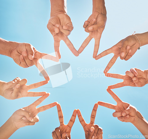 Image of Teamwork, community and group support with fingers in a star shape from below against a blue sky background. A diverse crowd of people with hands joined together for motivation, unity and peace