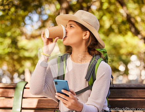 Image of Woman, phone and coffee in relax for backpacking on park bench for nature adventure in the outdoors. Female hiker or explorer relaxing on smartphone and drinking beverage with 5G connection for GPS