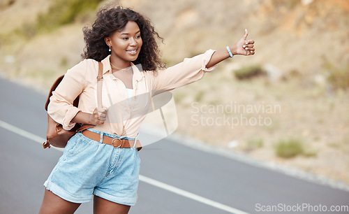 Image of Black woman, travel and thumbs up on the road for lift in nature for assistance, help or trip in the outdoors. African American female traveler or hitch hiker with roadside hand gesture for transport