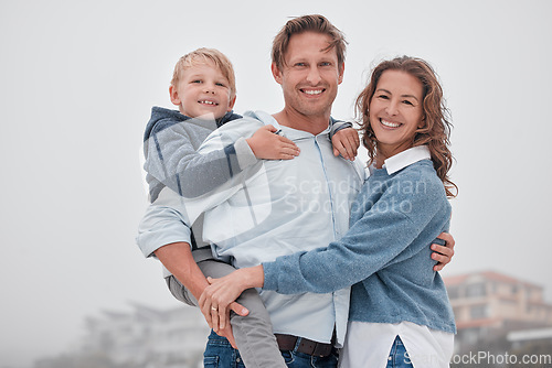 Image of Family, children and beach with a boy and parents by the sea or ocean for a holiday on a misty day. Portrait of kid, love and nature with a mother, father and daughter by the water during autumn