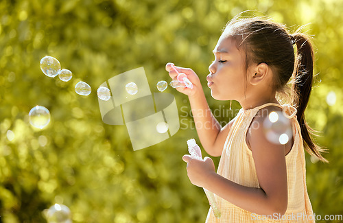 Image of Bubbles, outdoor and girl in a nature park feeling relax, playful and content by sunshine. Child from Taiwan blow a bubble in the spring sun feeling peace, calm and content with happiness on vacation