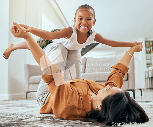 Image of Mother lift girl on floor and play in home living room for family love, care and wellness. Happy kid play fun youth game with mom and bond in house lounge with smile, happiness or relationship