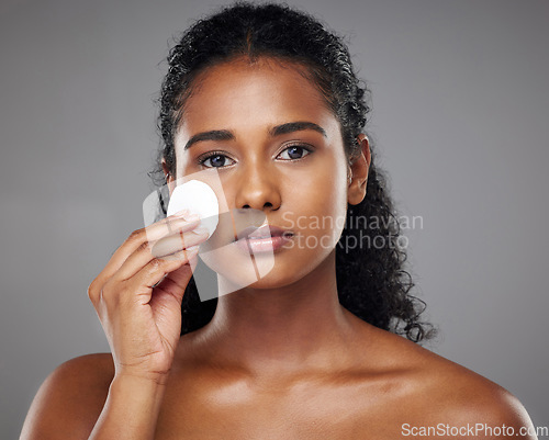 Image of Beauty, face and cotton pad with a model black woman exfoliating her skin in studio on a gray background. Cosmetics, treatment and skincare with an attractive young female using a natural product