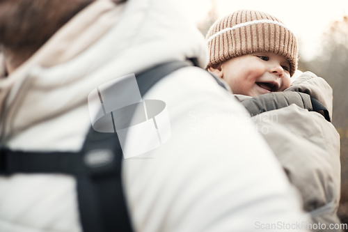 Image of Sporty father carrying his infant son wearing winter jumpsuit and cap in backpack carrier hiking in autumn forest.