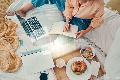 Image of Marketing, laptop and woman writing with breakfast on her bed, working and planning information for strategy from above. Remote employee with business notes, food and report for creative work on a pc