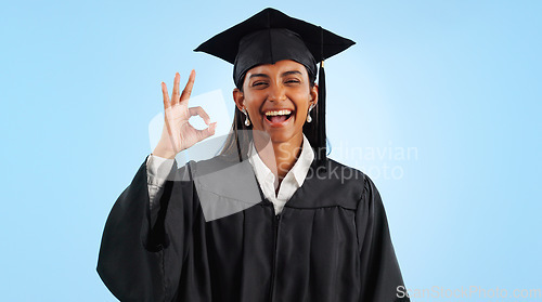 Image of Graduate woman, ok sign and smile in studio with review with vote, choice and support by blue background. Graduation, girl and portrait with icon, emoji or decision with celebration, goals or success