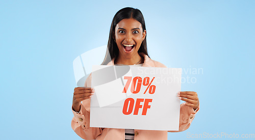 Image of Woman, promotion poster and portrait with sale, discount and billboard in studio. Excited, smile and happy from savings and deal paper with banner and promo with blue background and price decrease