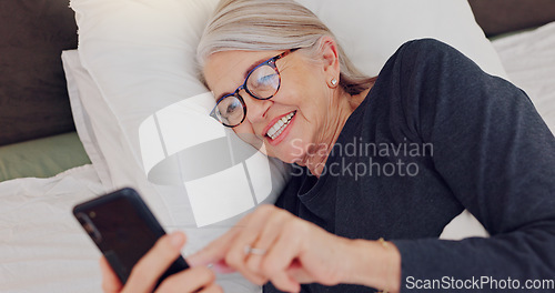 Image of Happy, senior woman and reading with phone in bed or streaming funny, comedy or meme on social media. Elderly person, smile or relax with cellphone at night in bedroom with communication or chat