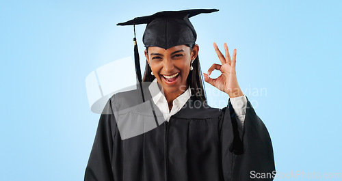 Image of Woman, ok sign and smile for graduation in studio with review with vote, choice or support by blue background. Student girl, portrait and celebration for icon, emoji or decision for success with goal
