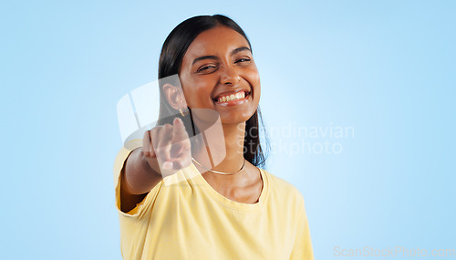 Image of Woman, portrait and pointing to you in studio for choice, decision of winner and vote for volunteering on blue background. Happy indian model show finger for recruitment, hiring emoji and invitation