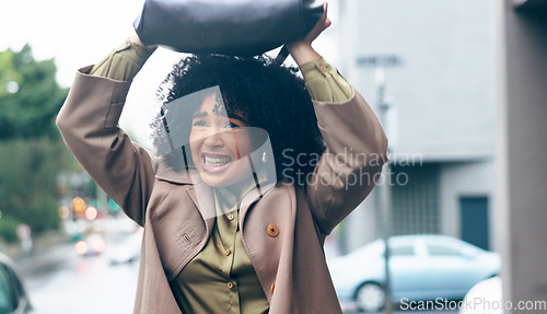 Image of Rain, woman and bag in city for safety. security and shield with frustrated, sad or mad expression. Winter, african person and handbag on head for cover, water drops or protection in Cape Town road