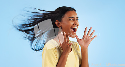 Image of Woman, scream and wind for hair in studio for mock up on blue background with good news. Indian person, happy and smile in excitement for winning with success, celebration or announcement in space