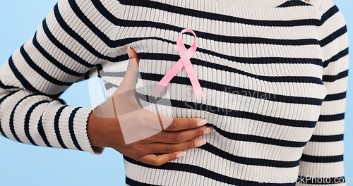 Image of Hand, show pink ribbon and breast cancer support with awareness and health icon on blue background. Person in studio, medical symbol and wellness with care, trust and kindness in solidarity campaign