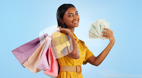 Image of Woman, shopping bag and cash fan, wealth and commerce with customer in portrait on blue background. Money, financial freedom and retail, fashion and product choice, rich and store discount in studio