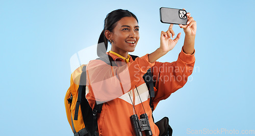 Image of Hiking studio, phone photo and woman trekking, backpacking and take picture of landmark, sightseeing or holiday. Freedom, vacation camper and smartphone photography for tour memory on blue background