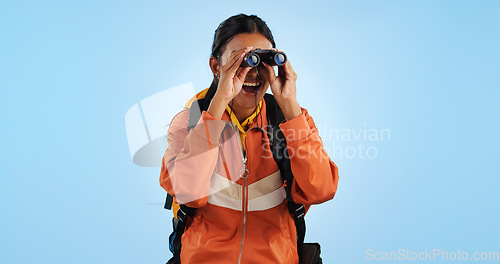 Image of Hiking studio, binocular and woman watch trekking, backpacking and travel adventure view, sightseeing or bird watching. Wow, journey and happy camper vacation, freedom or discovery on blue background