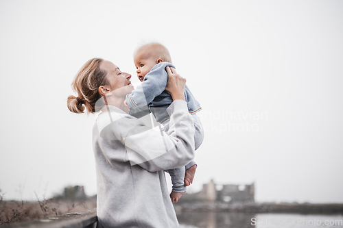 Image of Tender woman caressing her little baby boy infant child outdoors on autumn trip to Secovlje salinas landscape park, Slovenia. Mother's unconditional love for her child.