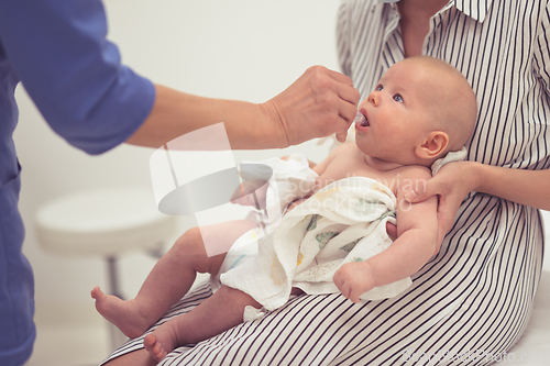 Image of Pediatrician administring oral vaccination against rotavirus infection to little baby in presence of his mother. Children health care and disease prevention