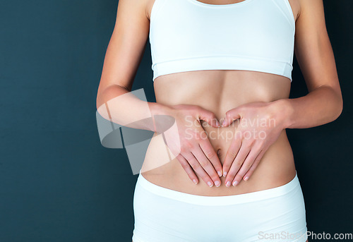 Image of Woman, hands and stomach in fitness, lose weight or diet against a studio background. Closeup of female person or model holding tummy for body care, liposuction or natural nutrition on mockup space