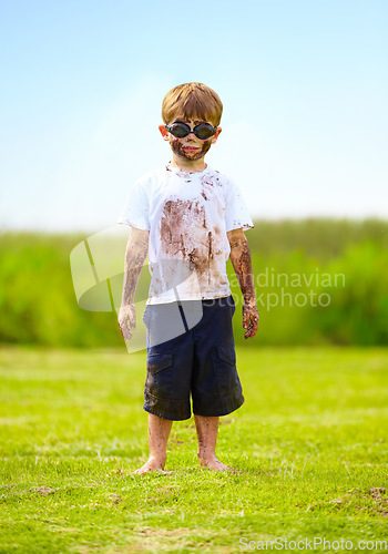 Image of Child, boy or mud on face with goggles in garden, grass or field for playing, fun and summer weather. Kid, person or eyewear covered in dirt on lawn or backyard for muddy play, childhood or enjoyment