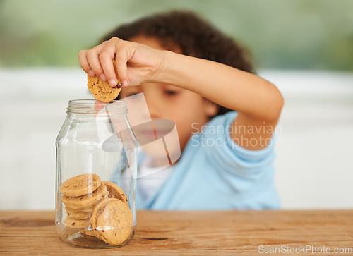 Image of Craving, cookie jar and boy child by the kitchen counter eating a sweet snack or treat at home. Smile, dessert and cute hungry young kid enjoying biscuits by a wooden table in a modern family house.