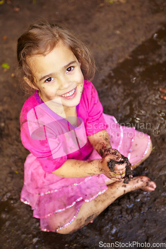 Image of Girl, child and portrait with smile in mud for freedom, playing and muddy fun in sunshine weather or outdoor. Kid, female and face of person with happiness for activity, enjoyment and relax in dirt