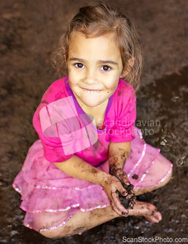 Image of Girl, kid and portrait with smile in mud for freedom, playing and muddy fun in sunshine weather or outdoor. Child, female and face of person with happiness for activity, enjoyment and relax in dirt