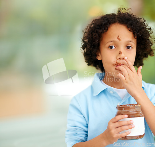 Image of Cute, portrait and kid with chocolate spread at a home with delicious, sweet snack or treat. Smile, happy and face of young boy child from Mexico eating nutella jar licking lips at modern house.