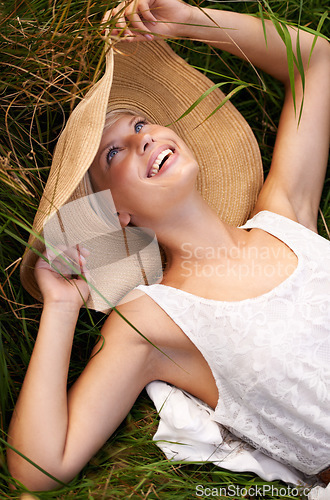 Image of Hat, woman and relax on grass or lawn with happiness and freedom in summer. Outdoor, fashion and girl lying on lawn with a smile on face for holiday, vacation or free time in nature with wellness