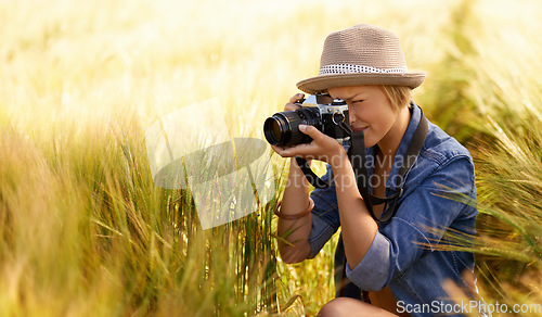 Image of Woman, camera and photography in grass with travel, vacation and holiday with wheat field and plants. Nature, photographer and outdoor with blog and countryside with photo for adventure and journey