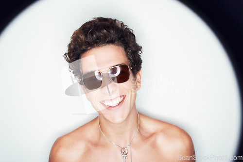 Image of Man, sunglasses and smile in studio with spotlight, fashion or shirtless with edgy punk style by background. Person, fashion and happy by halo for confidence, attitude or jewelry for trendy aesthetic