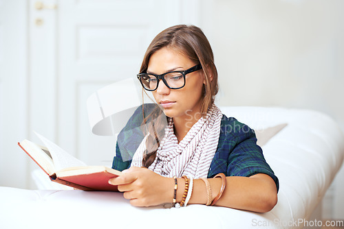 Image of Thinking, reading and woman on sofa with book, knowledge and learning with literature in home. Relax, paperback and studying in apartment, girl in glasses on couch with story journal in living room.